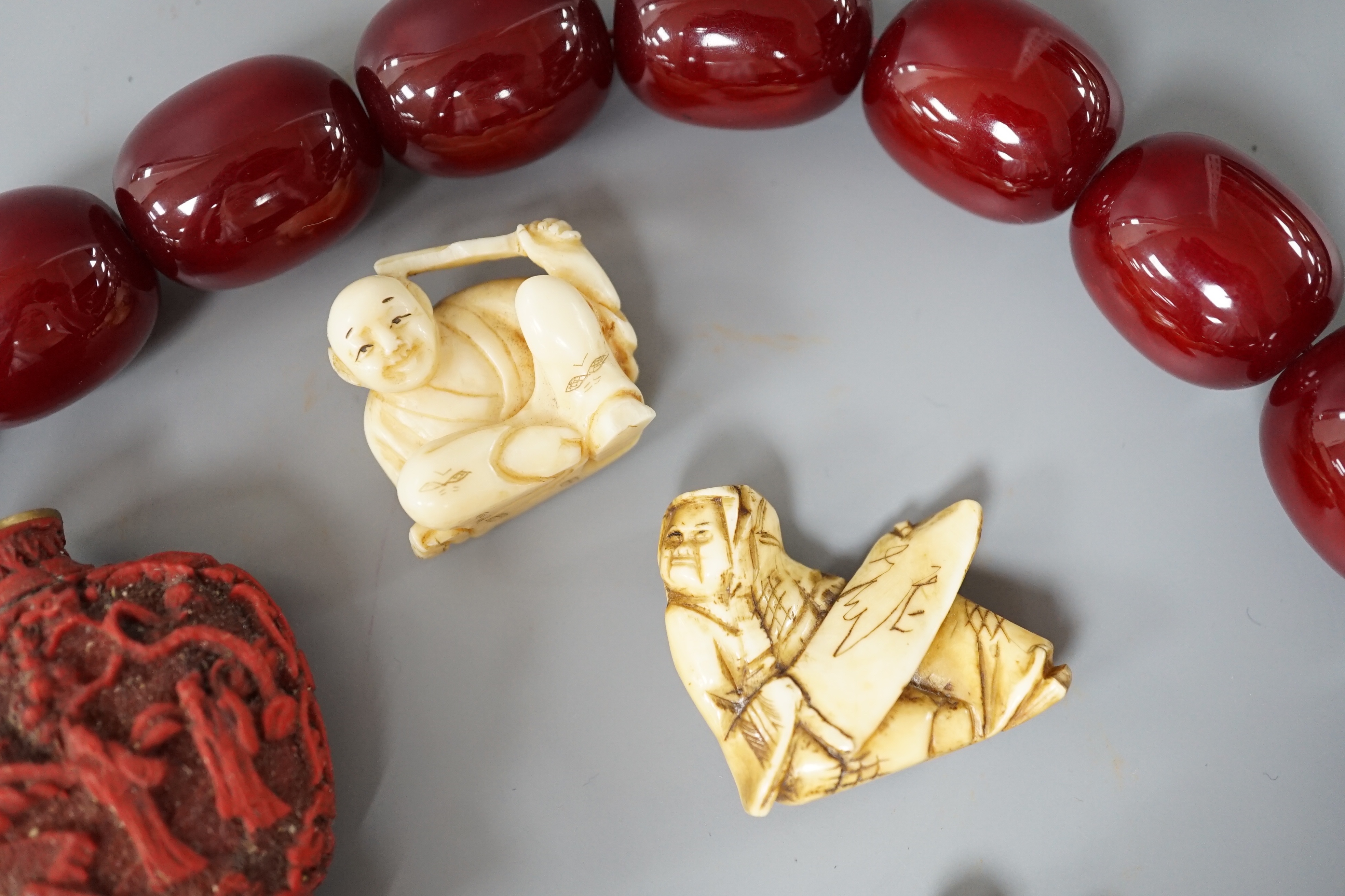 Assorted Chinese and Japanese Ivory and wood carvings, a scent bottle and a simulated cherry amber bead necklace, Necklace 52 cms long.